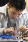 Undergraduate student Tom Chia test the circuit board of a muscle-activated massage pad prototype in an Engineering Centers lab.
